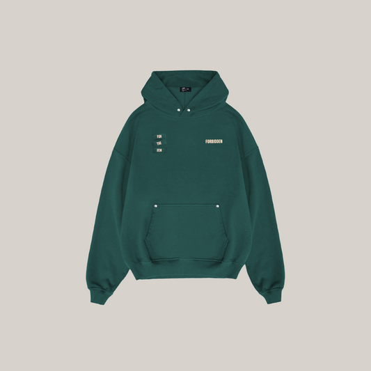 Dark green hoodie shown from the back featuring bold “FORBIDDEN” text, a small “For the Few” label, and a minimalist inspirational slogan printed at the center.