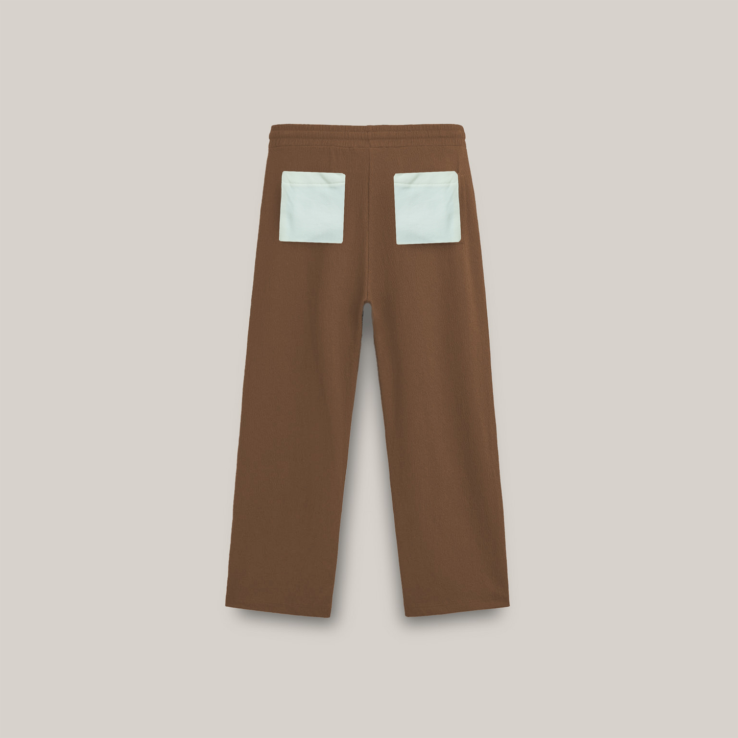 Brown straight-leg pants with a drawstring waist and beige sunflower embroidery near the bottom of both legs, along with a small “forbidden” text logo on the upper left side.