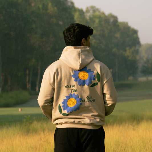 Cozy beige hoodie with blue flowers and the text across the chest.
