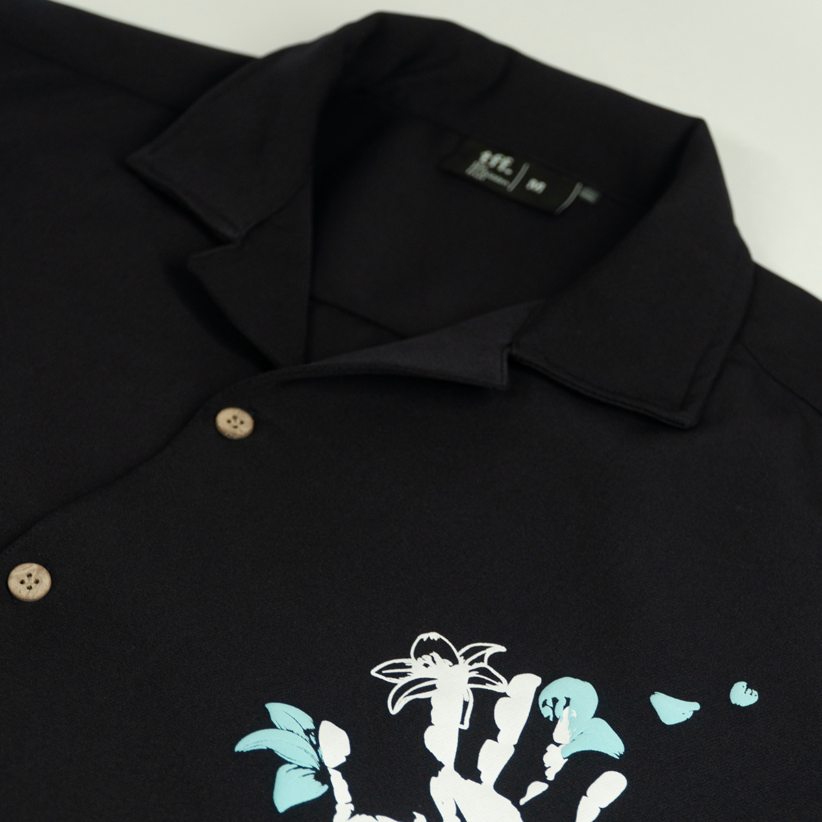 Navy blue short-sleeve shirt featuring a white handprint, blue butterflies, and floral designs. The word "Forbidden" is embroidered in white.