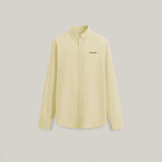 A light yellow long-sleeve button-up shirt with "Forbidden" embroidered in black on the chest, set against a plain beige background. Simple and elegant.