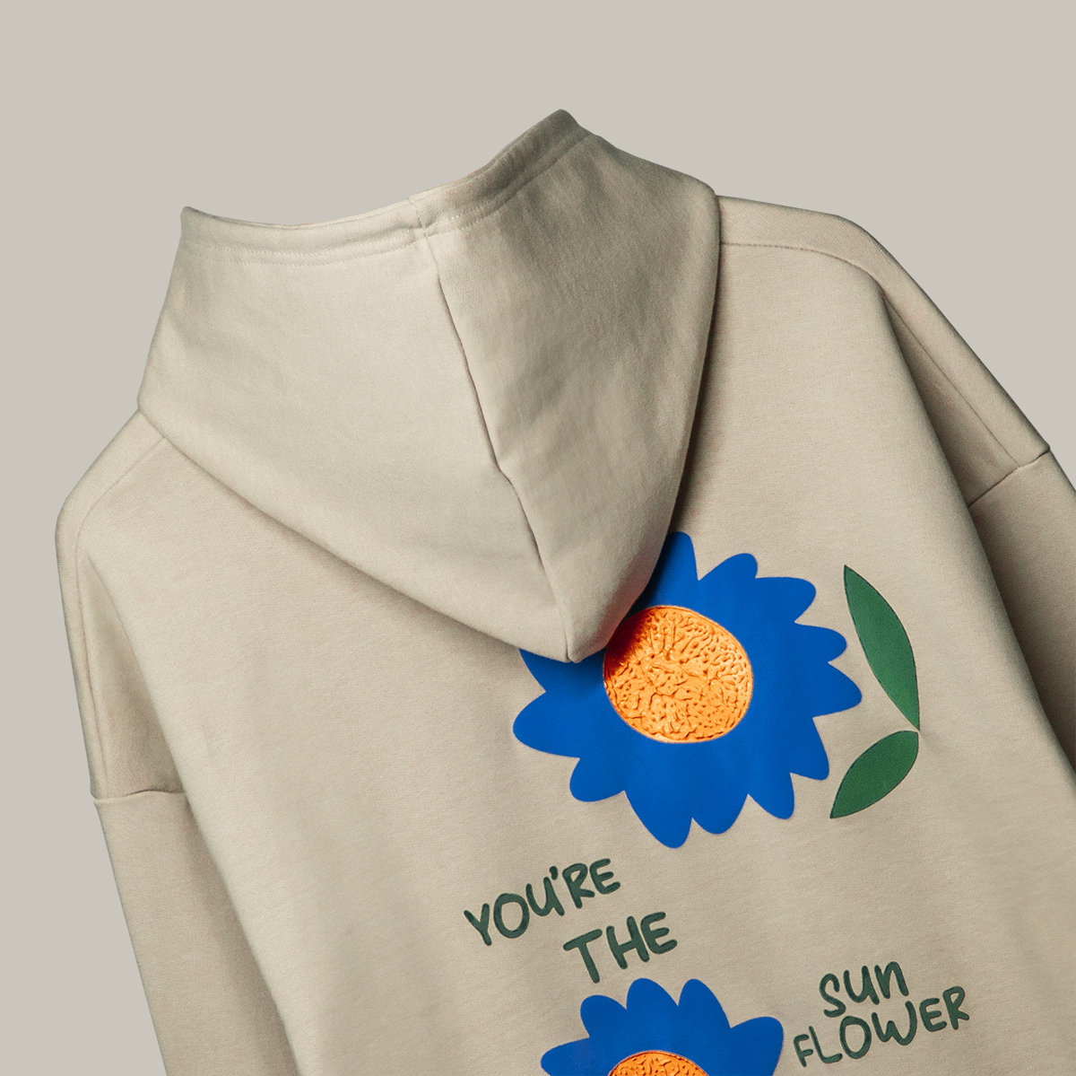 Cozy beige hoodie with blue flowers and the text across the chest.