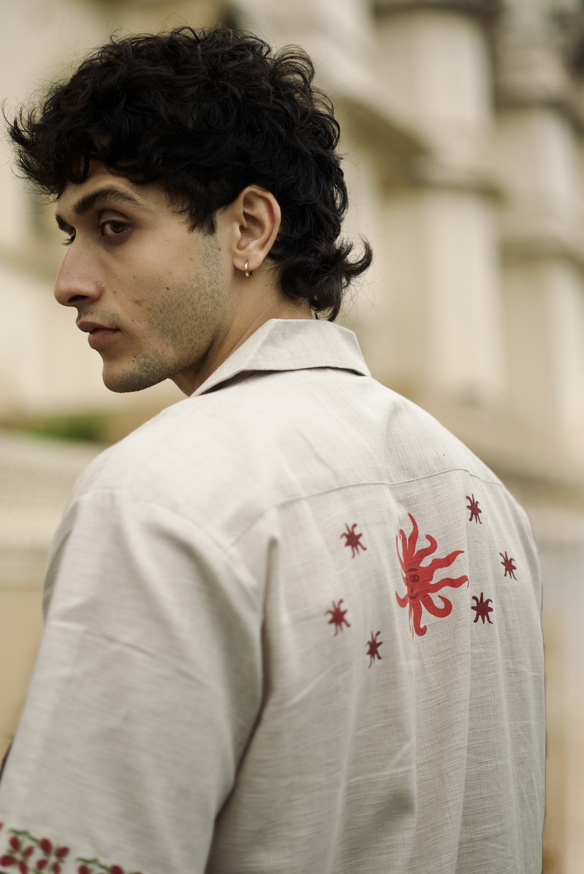 Short-sleeve beige button-up shirt, featuring decorative on the sleeves and two stylized tree graphics with star along with the word “Forbidden” embroidered on the chest.