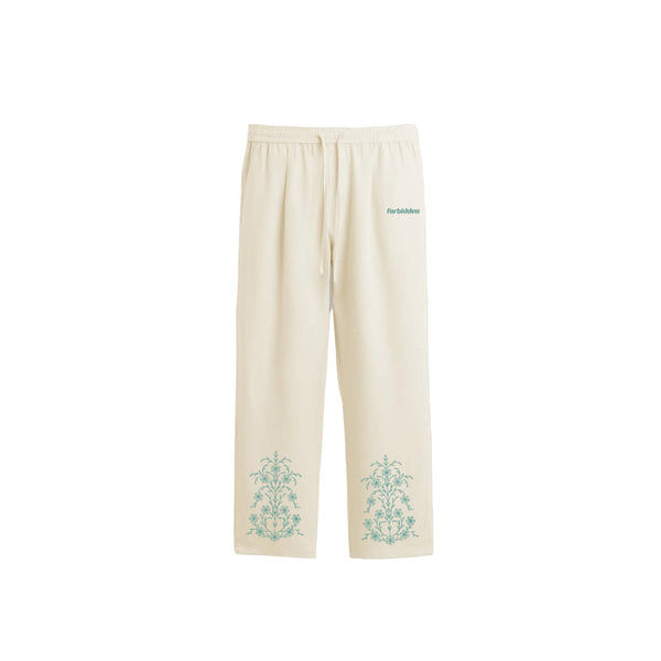 Cream-colored drawstring sweatpants with a relaxed, straight-leg fit. They feature teal ornate floral motifs near the bottom of each leg and a small teal logo on the upper left thigh.