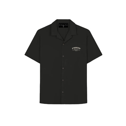 Model wearing a black short-sleeve button-up shirt with a relaxed collar and a small white “FRBDN” graphic on the left chest, paired with grey trousers.